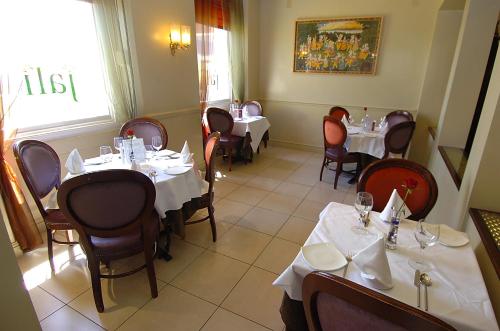 海斯廷斯卡茨沃斯酒店的餐厅配有桌椅和白色的桌布
