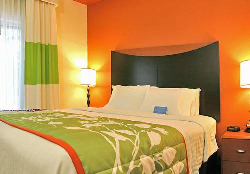 布伦瑞克不伦瑞克费尔菲尔德套房客栈的一间卧室配有一张带橙色墙壁的大床