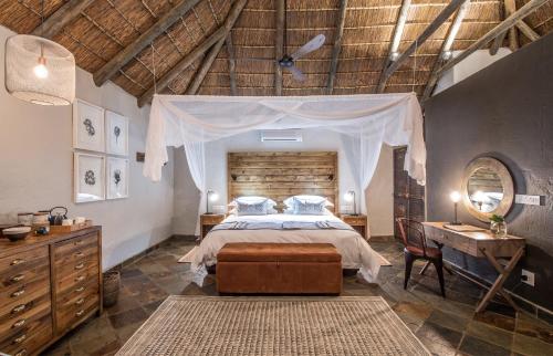 SidburyLalibela Game Reserve - Inzolo Lodge的一间卧室配有一张床、梳妆台和桌子
