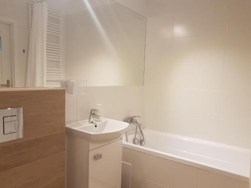 华沙Hennela Apartment的白色的浴室设有水槽和浴缸。