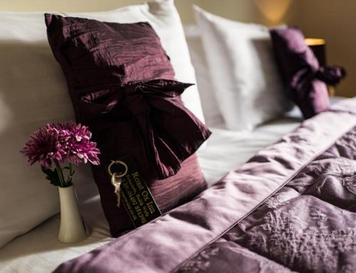比尔斯韦尔斯The Roast Ox Inn的一张带紫色枕头的床和一个花瓶