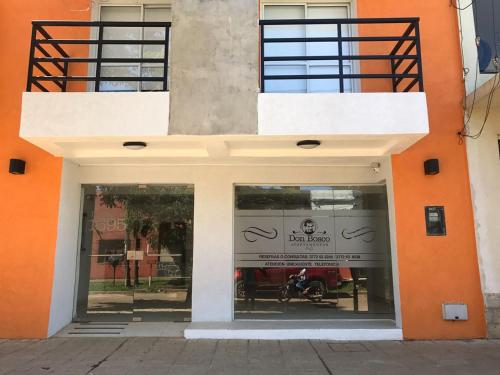 帕索德洛斯利布雷斯Apartamentos Don Bosco的橙色和白色的建筑,窗户上放着摩托车