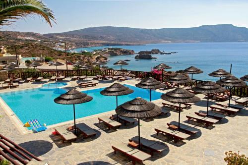 阿莫皮Aegean Village Beachfront Resort的一个带椅子和遮阳伞的游泳池的度假酒店