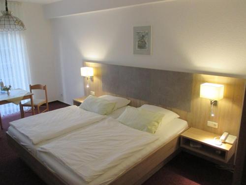 鲁特斯塔德·斯塔文哈瑞特霍夫酒店的一间卧室配有一张带两盏灯的大型白色床。