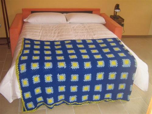 卡尼洛瑞维拉Il Pergolato的床上有蓝色和黄色的毯子