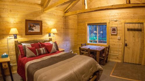 希利Denali Tri-Valley Cabins的一间卧室配有一张床、一张桌子和一个窗户。