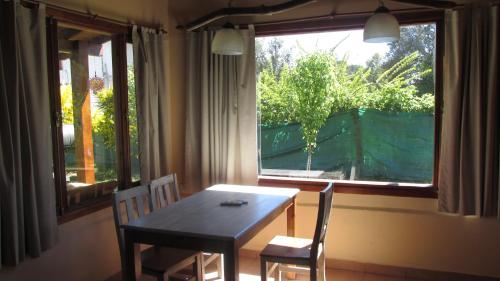 普埃洛湖Cabañas Peñi Huen的一间带桌子和两把椅子的用餐室以及窗户。