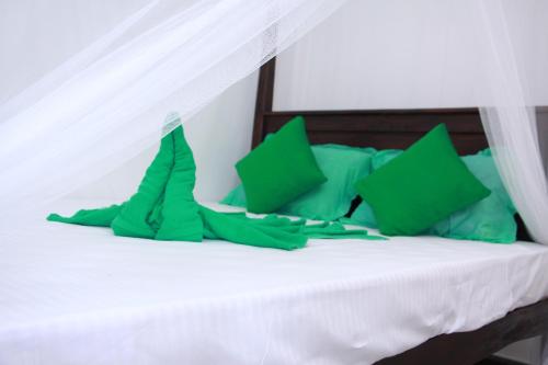 米瑞莎米瑞莎怀特旅馆的一张带绿色枕头和天蓬的白色床
