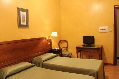 罗马费欧瑞酒店的酒店客房设有两张床、一张桌子和一台电视。