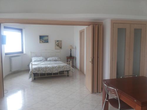 奥斯图尼Attico Ostuni的一间卧室配有一张床、一张桌子和一个窗户。