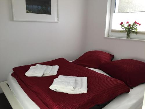 约阿希姆斯塔尔Ferienwohnung Felix am See的一张床上铺有红色毯子和白色毛巾的床