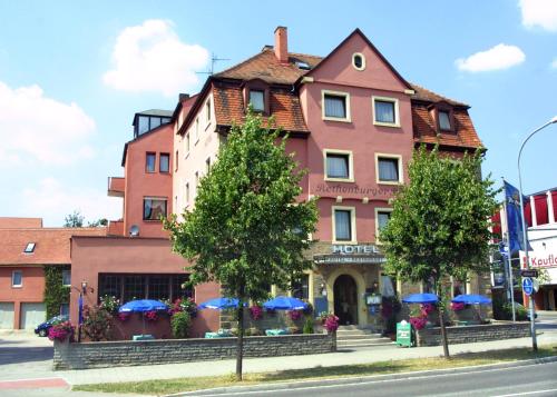 罗滕堡罗藤伯格酒店的一条街道上带蓝色遮阳伞的粉红色建筑