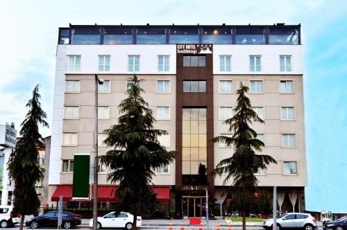 奥尔杜Baliktasi City Hotel & Spa的一座高大的白色建筑,前面有树木