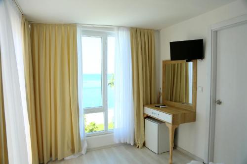 凯麦尔Olimpos Beach Hotel by RRH&R的客房设有带书桌和镜子的大窗户。