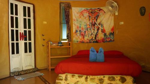 拜县拜县普拉那旅馆的卧室配有红色的床和墙上的绘画