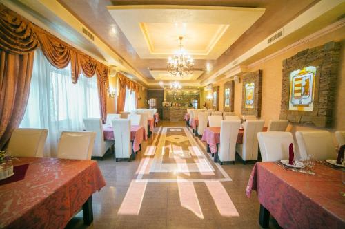 索洛钦База відпочинку ЕЛЬДОРАДО的餐厅设有桌子、白色椅子和吊灯
