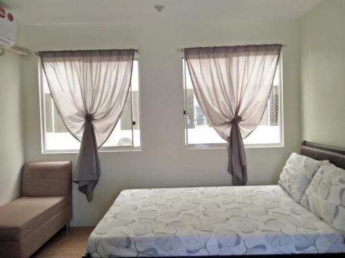 宿务圣雷莫绿洲公寓的一间卧室配有一张床、一张沙发和两个窗户。
