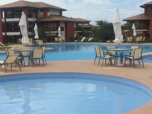 普拉亚多village na praia do forte的酒店前方设有一座带桌椅的游泳池