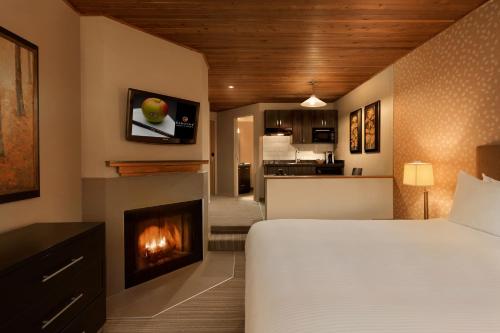 惠斯勒惠斯勒行政酒店的一间卧室配有一张床和一个壁炉