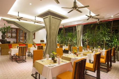 暹粒金庙别墅酒店的一间设有白色桌椅的餐厅,种植了植物