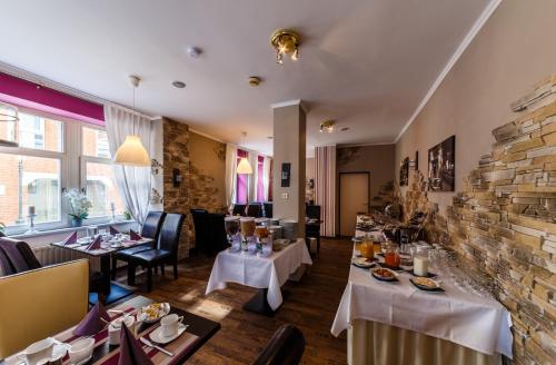 施托尔贝格City Hotel Stolberg的一间带桌椅的餐厅以及砖墙