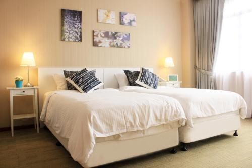 新加坡Alocassia Serviced Apartments的一间卧室配有两张带白色毯子和枕头的床