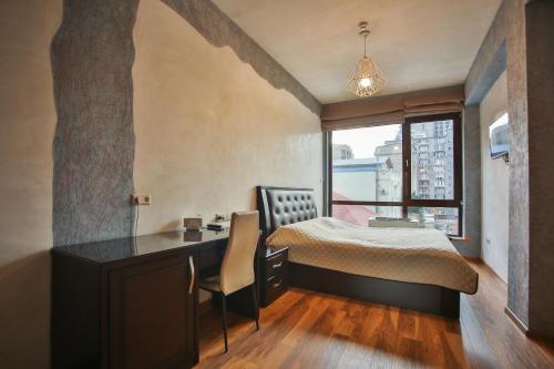 第比利斯Hotel Wine Palace的一间卧室配有一张床、一张书桌和一个窗户。
