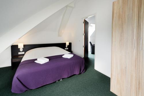 Milheeze尼德海德酒店及餐厅的一间卧室配有一张带紫色床单和毛巾的床。