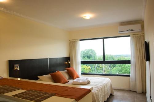 维多利亚Rio Manso Apartamentos的一间卧室设有一张大床和大窗户