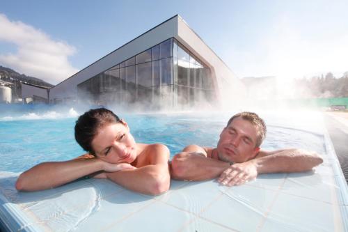 阿尔滕马克特蓬高Ferienwohnung Konold的男人和女人在带喷泉的热水浴缸中游泳