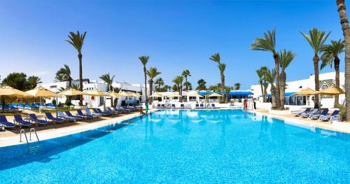 阿格希尔Hari Club Beach Resort的一个带椅子和棕榈树的大型游泳池