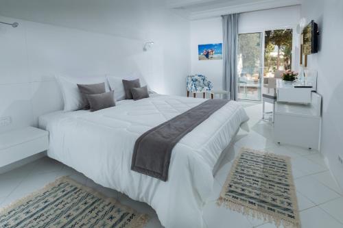 阿格希尔Hari Club Beach Resort的白色的卧室配有一张白色的大床和一张沙发