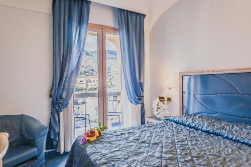伊斯基亚亚拉贡宫温泉酒店的一间卧室设有蓝色的床和窗户。