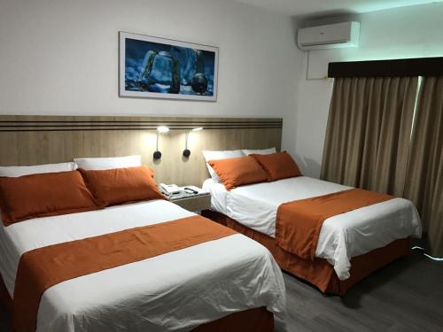 曼塔Hotel Mar Azul的酒店客房带两张带橙色床单的床