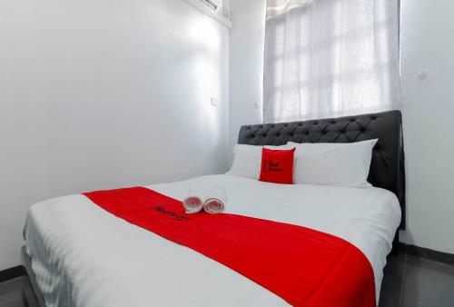 巴淡岛中心RedDoorz Plus near Batam City Square的一间卧室配有一张带红白毯子的床