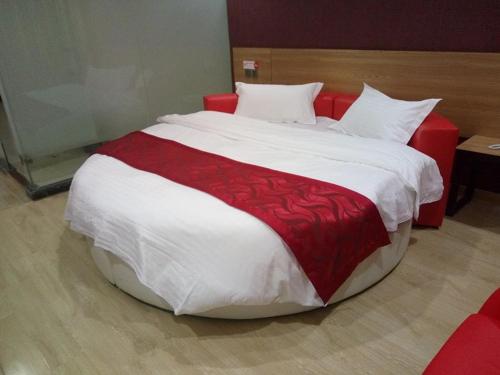 Wujiayao尚客优连锁江苏泰州泰兴市星火路店的客房内一张红色和白色的大床
