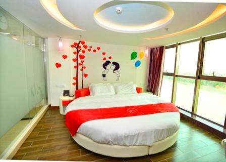 梅州尚客优连锁广东梅州梅县丽江湾店的卧室配有一张墙上心灵的大床