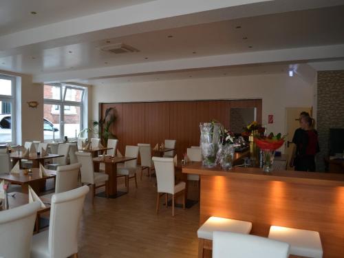 赖讷莱茵河-奥特斯塔德特德酒店的一间设有桌子和白色椅子的用餐室,以及女服务员