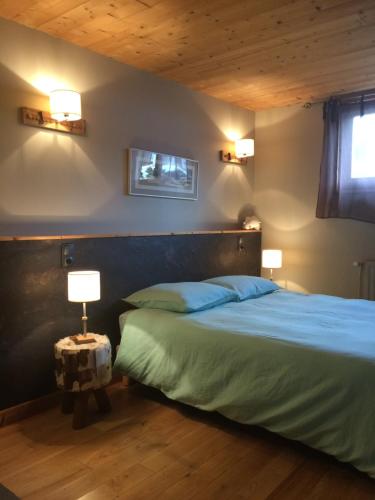 Les FourgsAu Charnet的一间卧室配有一张带蓝色床单的床和两盏灯。
