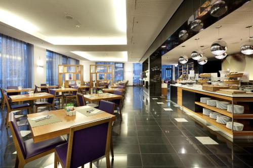 慕尼黑欧洲之星大中心酒店的餐厅设有木桌、椅子和窗户。