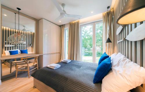 波别罗沃Baltic Melody Apartament Pobierowo的一间卧室配有一张带蓝色枕头的床和一张书桌