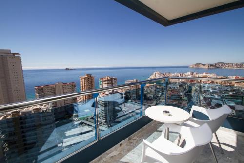贝尼多姆马德里中心酒店的阳台配有白色的桌椅,享有海景。