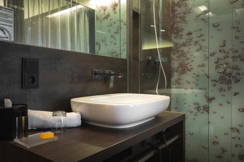 凯撒斯劳滕凯撒斯劳滕萨克斯城市设计酒店的一间带水槽和玻璃淋浴的浴室