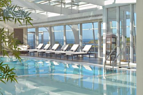 阿尔宗Miramar La Cigale Hotel Thalasso & Spa的一座带白色躺椅的游泳池