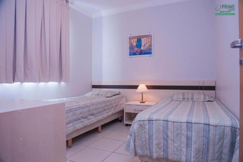 热河市Prime Hotel Águas da Serra的一间卧室配有两张床和一张带台灯的桌子