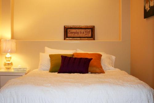 基洛纳Quail Ridge的卧室配有白色床和橙色及紫色枕头