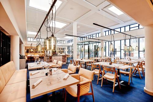哥本哈根Nobis Hotel Copenhagen, a Member of Design Hotels™的餐厅设有木桌、椅子和窗户。