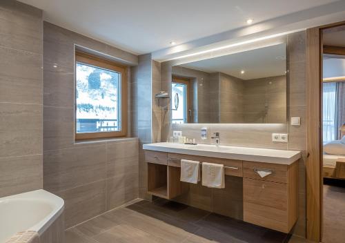 奥伯古格尔Apartment Alpenland的一间带水槽、浴缸和镜子的浴室