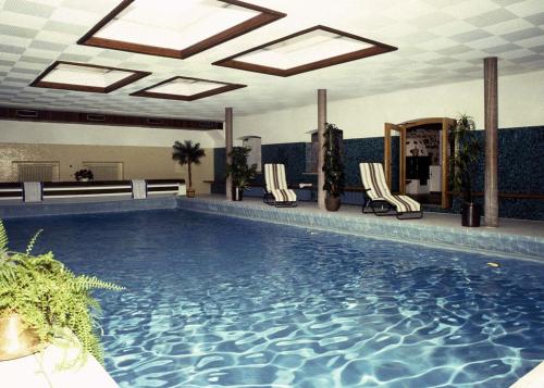 若特阿赫-埃根Gästehaus Pfatischer Hotel Fewo的酒店设有一个大型游泳池,配有椅子