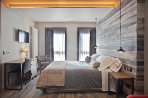 贝纳斯克Hotel Boutique La Neu的一间卧室配有一张大床和一张书桌